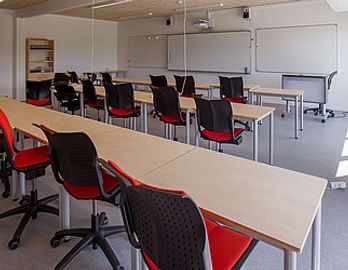 Undervisning JK Pavillioner - Klasselokale med sorte og røde stole opstillet